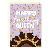 The Queen Birthday Card by Natalie Henry Charles features Happy Birthday Queen on lavender, with orange and white flowers and a womans curly hair topped with blooms. Printed in the USA.