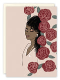 The Bella Roses Birthday Card by Amy Slaughter features a dark-skinned woman with curly hair, white top, and pearl earrings, eyes closed amid bold red roses and green leaves on light beige recycled paper.