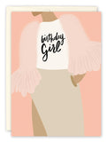 The Birthday Girl Card by Amy Slaughter features a woman in a pink feathered jacket and beige skirt with birthday Girl on her shirt, set against a soft peach background. Printed on recycled paper.