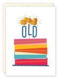 The Old Birthday Card by Andrea Williams features a striped, multi-layered cake and candles spelling OLD with gold dot flames on a white background, crafted from recycled paper for an eco-friendly birthday greeting.
