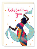 Introducing the Chevron Dress Birthday Card by Cherrymae Golston: This premium birthday card showcases a vibrant illustration of a person in a colorful dress holding two blue scarves, complemented by the text "Celebrating You" in red with playful orange dots in the background. Made from recycled paper, it's an ideal choice for sending heartfelt wishes while being eco-friendly.