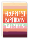 A Year Bolder Birthday Card by Lauren-Ashley Barnes features horizontal colorful stripes, Happiest Birthday Wishes in bold white letters, and a candle-shaped “I”—all on recycled paper.