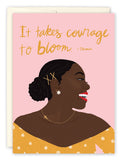 The Courage To Bloom Birthday Card by Lauren-Ashley Barnes features a smiling woman in a yellow floral top and gold accessories. Printed on recycled paper, the pink card displays gold It takes courage to bloom. A vibrant, versatile design.
