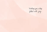The Lauren-Ashley Barnes Happy B-Day Birthday Card features a light peach, abstract patterned background on premium recycled paper, with Wishing you a day filled with joy elegantly scripted in the upper right corner.