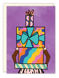 The Stacked Presents Birthday Card by Natalie Henry Charles features an illustration of arms holding a tall stack of colorful, patterned gift boxes with bright bows against a purple background—ideal for celebrating birthdays in style.