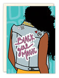 The Black Girl Magic Birthday Card by Natalie Henry Charles features an illustrated Black woman with long curly hair in a denim vest, Black Girl Magic on the back, set against a teal patterned background. Printed on recycled paper.