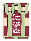 The Partner In Wine Birthday Card by Natalie Henry Charles features wine bottles on a light green background, with Happy Birthday to my partner in wine on the center bottle, printed on premium recycled paper.