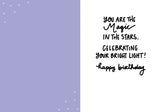 The Universe Birthday Card by Natalie Henry Charles features a purple left side with tiny white stars on high-quality recycled paper. The white right side reads in handwritten text: Magic in the stars—celebrating your bright light! Happy birthday.