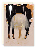 The Heels & Friends Birthday Card by Black Joy Paper features three stylish women—one in a tuxedo with heels, one in a black top and sparkly skirt, and another in a black one-shoulder jumpsuit—celebrating amid gold balloons and confetti.