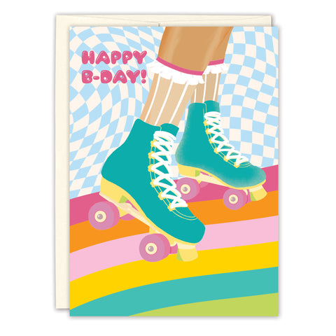 The Roller Skates Birthday Card by Lauren-Ashley Barnes features teal skates and white frilly socks, set against a colorful checkered blue background with rainbow stripes and “Happy B-Day!” in pink letters.