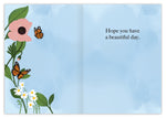 The Butterflies Birthday Card by Lauren-Ashley Barnes features pink and white flowers, green leaves, two orange butterflies, and “Hope you have a beautiful day.” on a blue background—colorful touches perfect for any birthday.